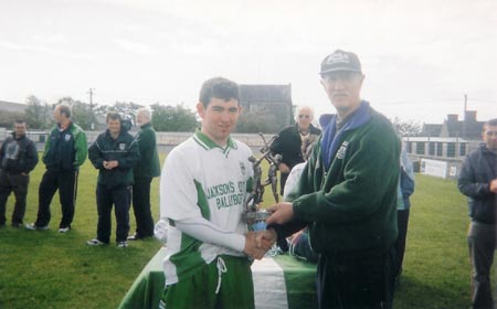 Martin 'Kerry' Ryan presenting the player of the tournament to Adam Gallinagh of McCumhaills.